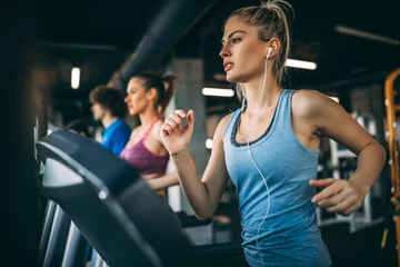 Young people running on a treadmill in health club.