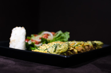 Japanese pan fry with salad and rice in black background.