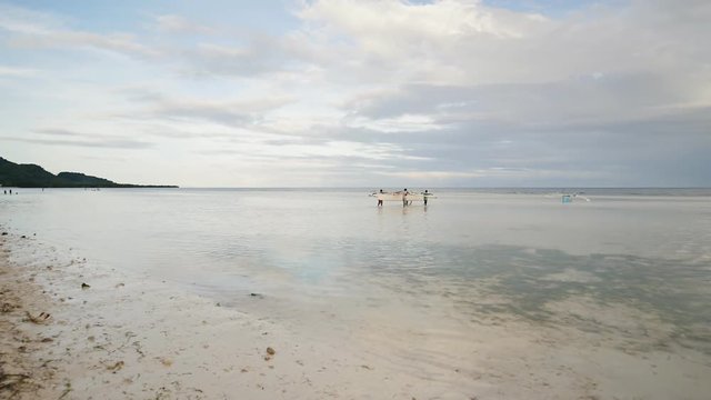 Fishermen carry a boat to the sea. Bohol Island. Philippines.