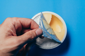Soft butter in the open lid plastic containing cup in the scene appear the aluminum foil unsealed