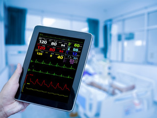 doctor's hand holding the tablet displaying ECG in the intensive care unit (ICU). process in blue tone.