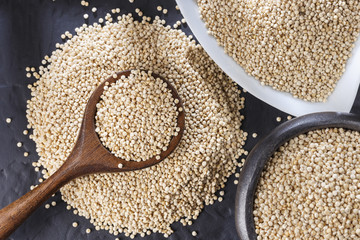 Quinoa grains with spoon and bowl on black background