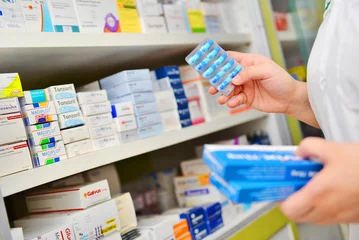 Papier Peint photo Lavable Pharmacie Pharmacien tenant une boîte à médicaments et un pack de capsules en pharmacie.