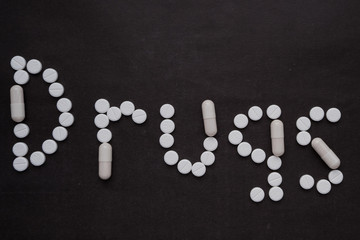 word "drugs" from pills on a black background