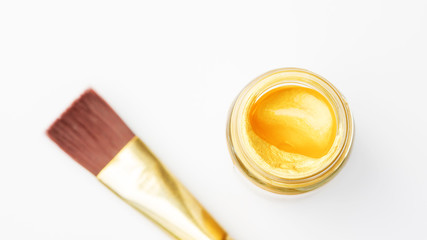 Gold colored poster watercolor bottle and paintbrush on white background.