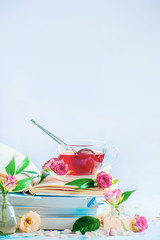Leisure and reading concept on a white background with copy space. Stack of white books with a cup of herbal tea.
