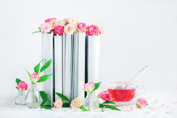 Leisure and reading concept on a white background with copy space. Stack of white books with a cup of herbal tea.