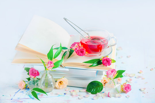 Stack of white books with a cup of herbal tea. High key still life with copy space. Spring leisure and reading concept. White on white.