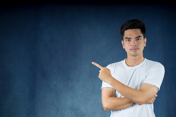 Portrait handsome young asian man wearing a white shirt shows finger direction isolated on dark background. Asia man people. business concept.Copy space.
