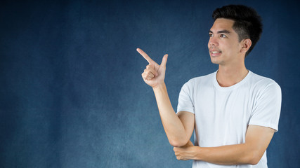 Portrait handsome young asian man wearing a white shirt shows finger direction isolated on dark background. Asia man people. business concept.Copy space.