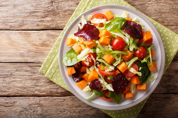 Fresh vegetarian salad with baked sweet potato, vegetables and herbs close-up on a plate. horizontal top view