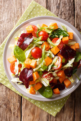 Delicious organic salad of sweet potato with fresh vegetables close-up on a plate. Vertical top view