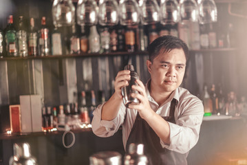 A bartender is mixing alcohol in a shaker to serve customers in a nightclub.
