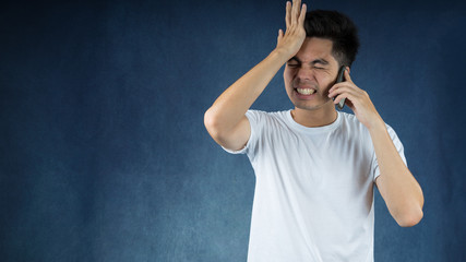 Portrait handsome young asian man wearing a white t-shirt holding smart phone feeling stressful isolated on black background. Businessman concept. Asia people.