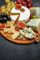 Brie cheese on a wooden Board with fresh figs and grapes