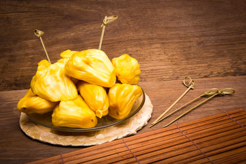 Jack fruit in wooden plate on old wood background.