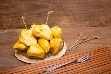 Jack fruit in wooden plate on old wood background.