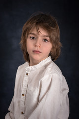 Retro a portrait of the little boy of the brunette in a white shirt on a dark background in studio