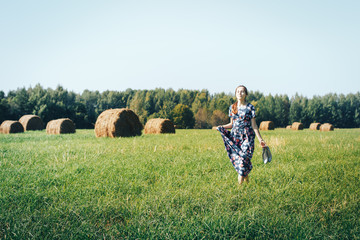 Naklejka na ściany i meble Teenager girl in an autumn field with hay stack