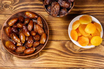 Dried apricots and dates fruit on wooden table. Top view