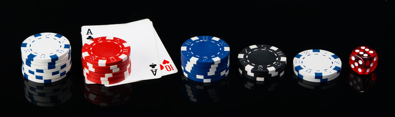 Obraz premium two cards and, laid out in a row, poker chips and a cube, on a black background