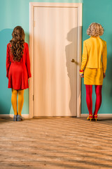 back view of retro styled women standing at door at colorful apartment, doll house concept