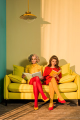 women in retro clothing reading books sitting on yellow sofa at bright apartment, doll house concept