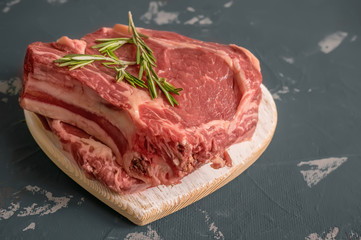 Cutting beef for grilling on a wooden cutting Board with Bay leaf, rosemary for marinade in a rustic style. Copy space.