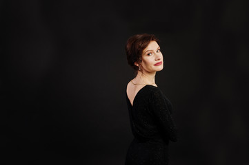 Elegance woman in black evening dress posed on studio isolated on black.