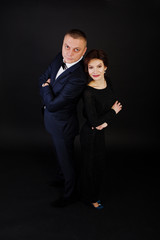 Elegance woman in black evening dress with man in suit posed on studio isolated on black. Duet couple of two.