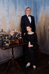 Elegance woman in black evening dress with man in suit posed on studio near retro phone. Duet couple of two.
