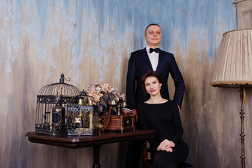 Elegance woman in black evening dress with man in suit posed on studio near retro phone. Duet couple of two.