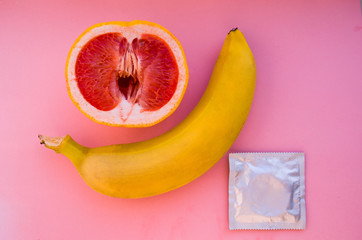 Banana and grapefruit with condom on pink background, Safe Sex Concept