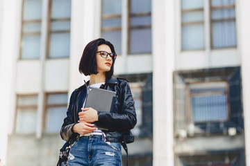 girl in glasses with tablet on background of building