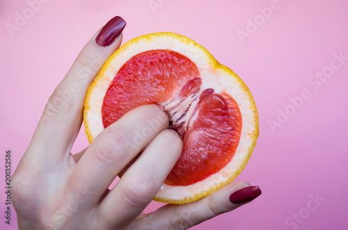 Two fingers on grapefruit on pink background. Sex concept Two fingers on grapefruit on pink background. Sex concept