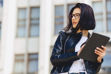 girl in glasses with tablet on background of building