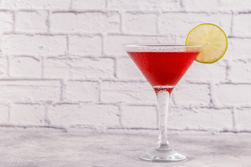 Glass of cosmopolitan cocktail decorated with lime