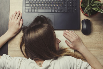 Young girl lies on laptops in a working environment. The concept of a long working day, fatigue, lack of sleep