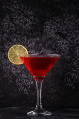 Glass of cosmopolitan cocktail decorated with lime