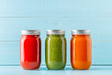 Orange/green/red colored smoothies / juice in a jar