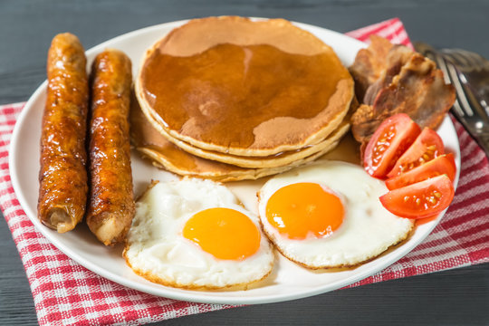 Pancake with egg, sausage, bacon and maple syrup