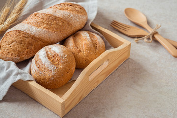 Bread and buns on wooden tray .
