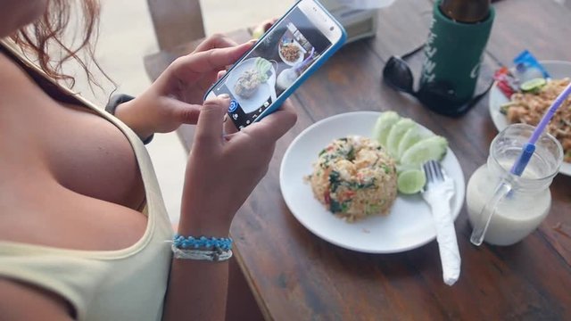 A young girl blogger makes a vertical photo of food on her phone. slow motion. 1920x1080. full hd