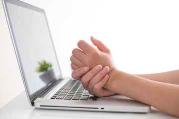 Woman holding her wrist pain from using computer. 