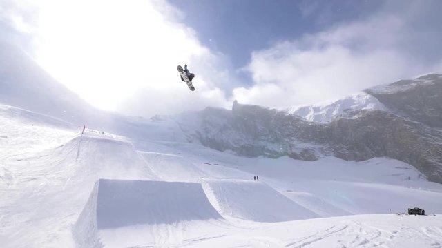 Professional snowboarder performs a cab ten double grab