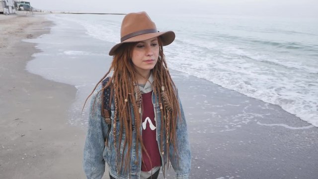 Young woman with corgi dog posing on the beach, girl with dreadlocks and hat with pet 