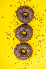 chocolate donuts with chocolate sprinkles on yellow background 