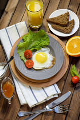 English Breakfast: fried egg, juice, cherry tomatoes, lettuce, grain bread, sauce, top view.