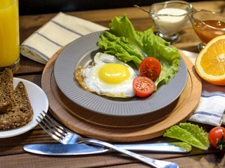 English Breakfast: fried egg, juice, cherry tomatoes, lettuce, grain bread, sauce, top view.