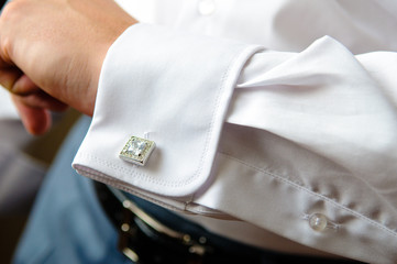 The groom fasten cufflinks on the cuffs of the shirt. The morning gatherings of the groom on the wedding day. Businessman fasten cufflinks on the cuffs of the shirt.